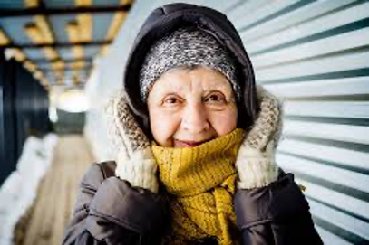 Elderly lady wrapped up in hat gloves and scarf to keep warm