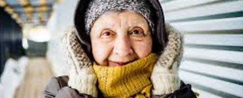 Elderly lady wrapped up with warm coat, scarf, gloves and hat to keep warm
